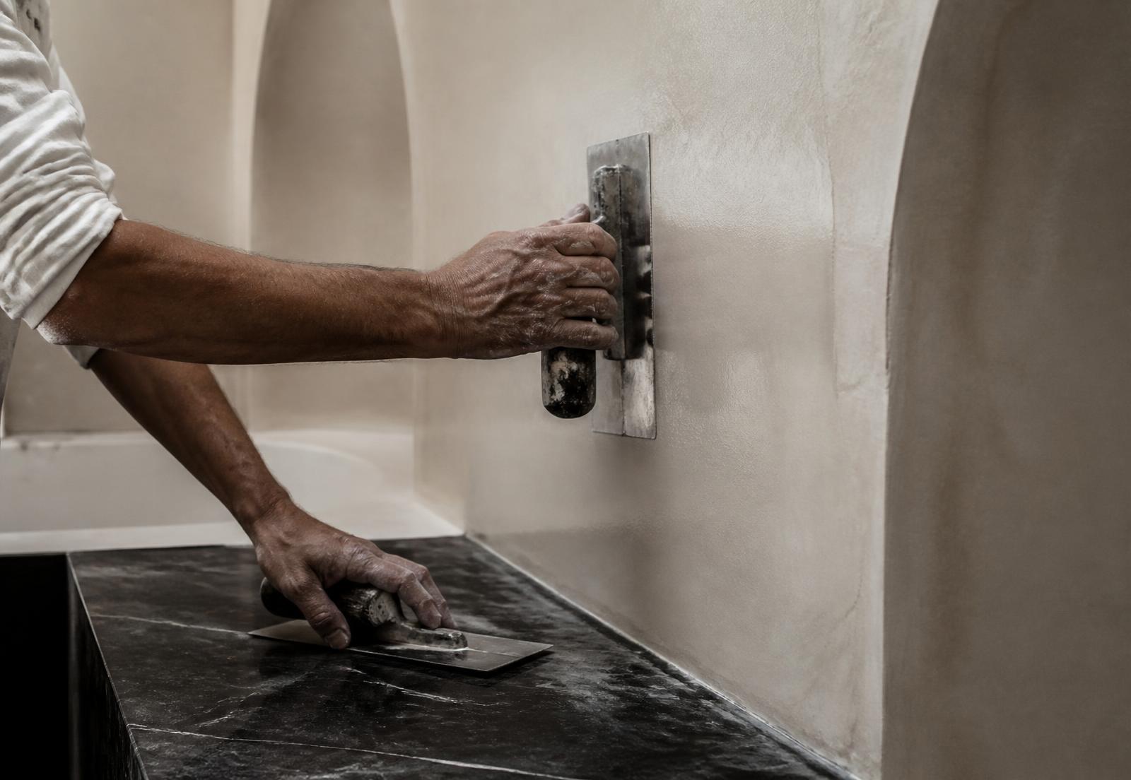Artisan hands polishing ivory tadelakt plaster above black stone