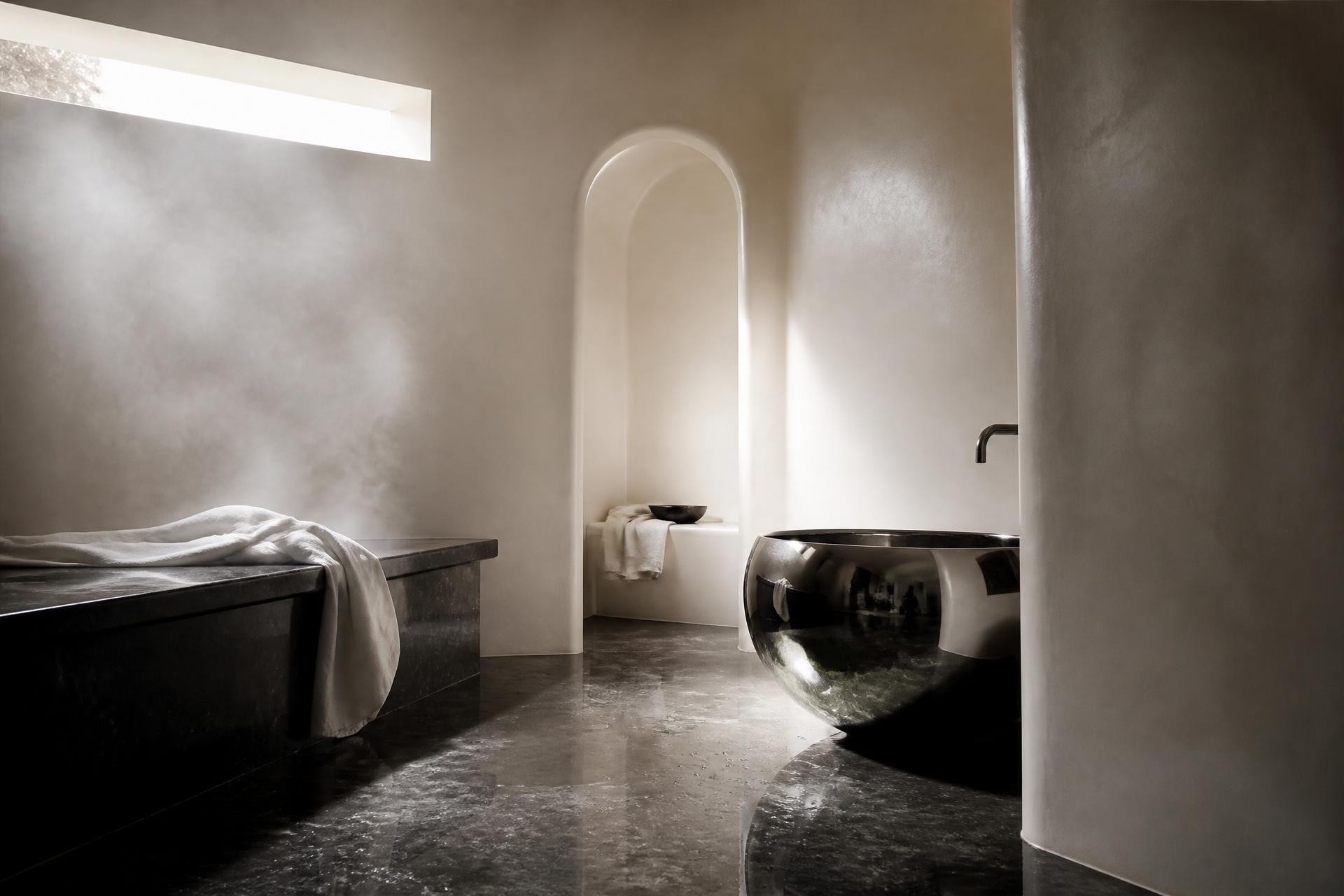 A contemporary private hammam in black stone and ivory tadelakt, filled with steam